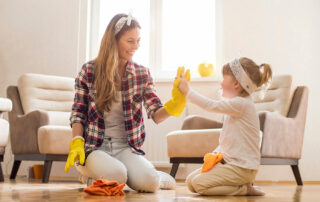 Woman and daughter high five while cleaning living room in downtown loft apartment