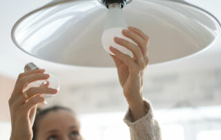 Woman changing lightbulb from incandescent light to LED lightbulb