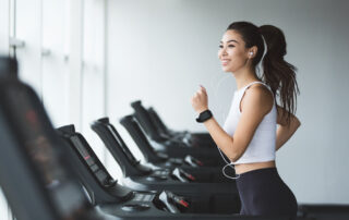 A happy woman jogging on a treadmill in the gym at the downtown apartments for rent